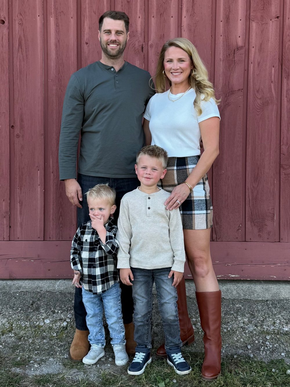 Eric with his wife and their two sons in front of a red barn